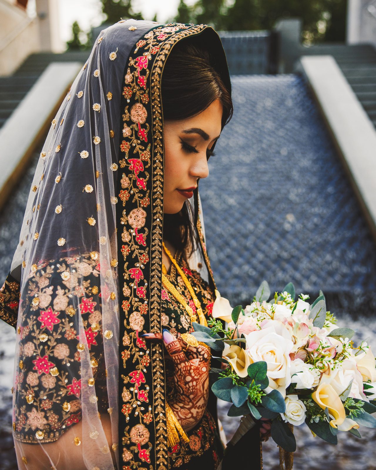 A bride in an embroidered dupatta holds her bouquet.