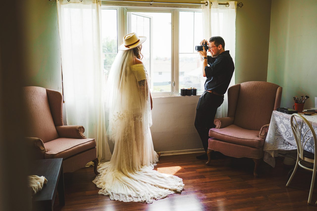 Jacob photographing a bride by a window in the quiet before the day begins.